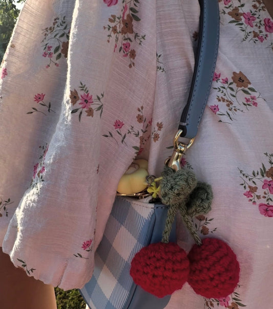 Red crochet cherries with green leaves clipped to a handbag